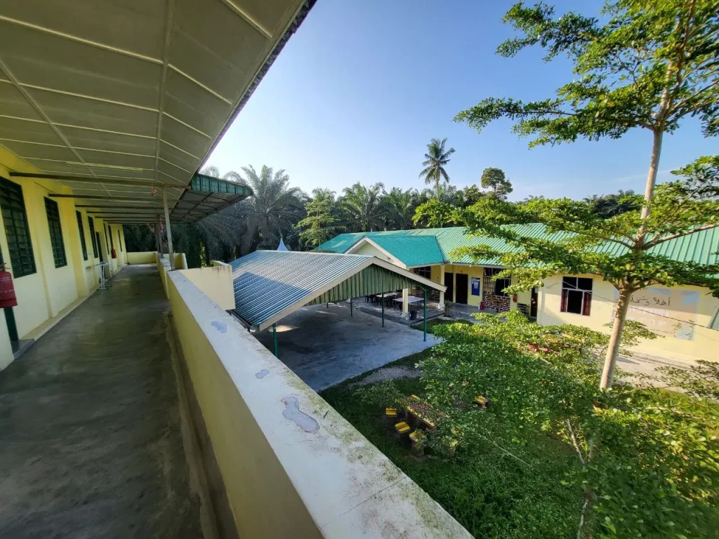 Pemandangan kawasan Maahad Tahfiz dari koridor bangunan dengan suasana hijau dan struktur sekolah di bahagian bawah.