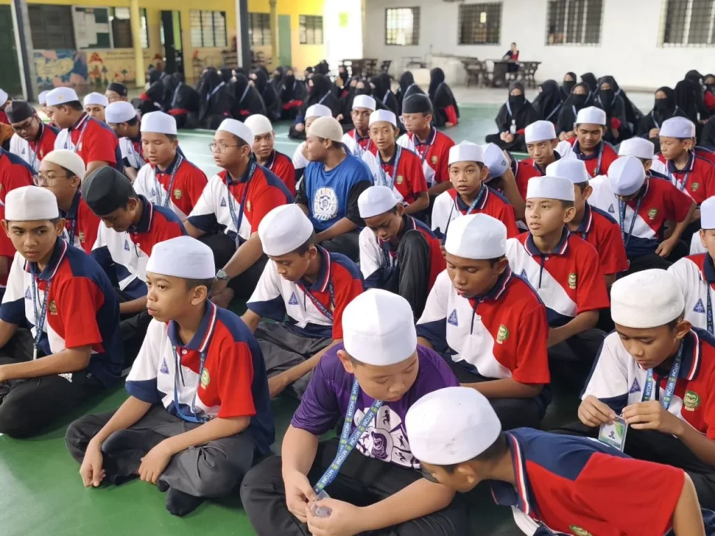 Pelajar tahfiz lelaki berkumpul dalam perhimpunan kokurikulum dengan pakaian seragam sukan.