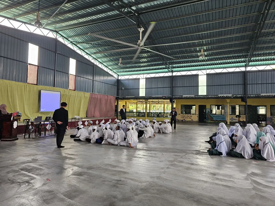 Pelajar tahfiz lelaki dan perempuan berhimpun dalam dewan tertutup untuk aktiviti atau majlis sekolah.
