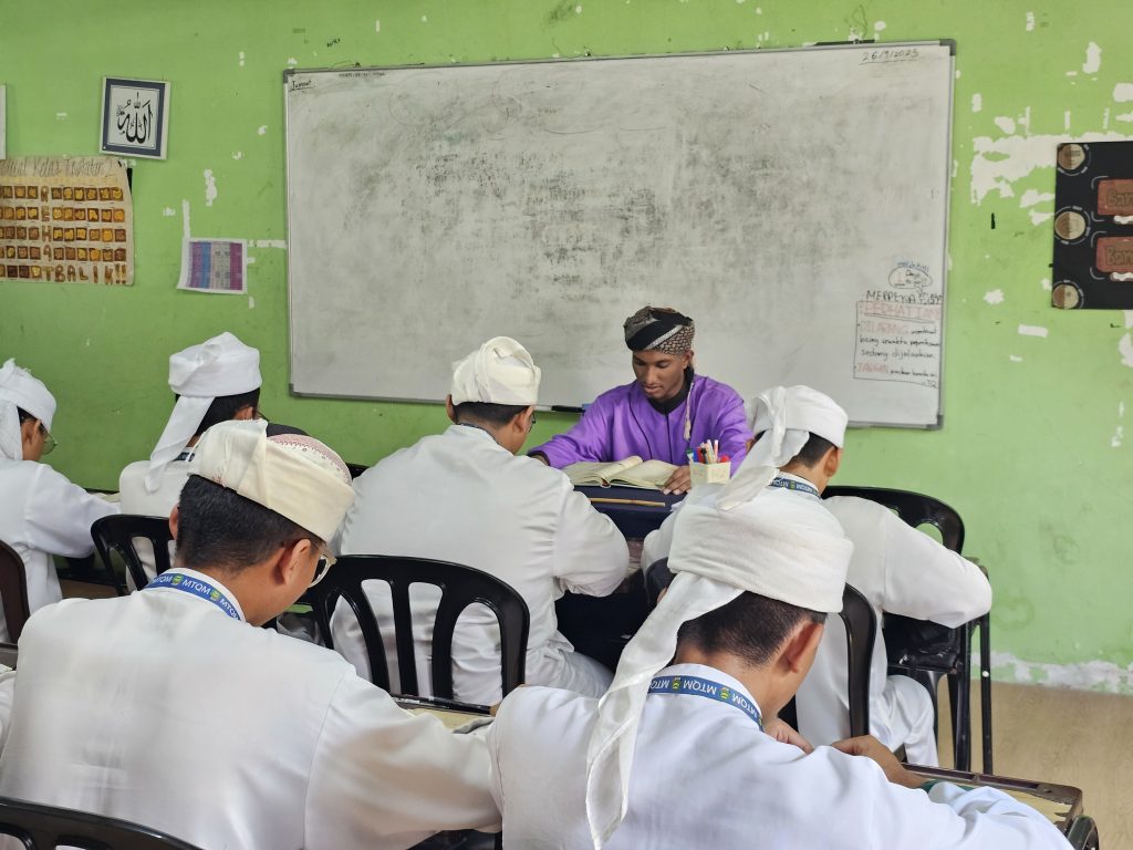 Pelajar tahfiz lelaki mengikuti sesi pembelajaran al-Quran bersama guru di dalam kelas.