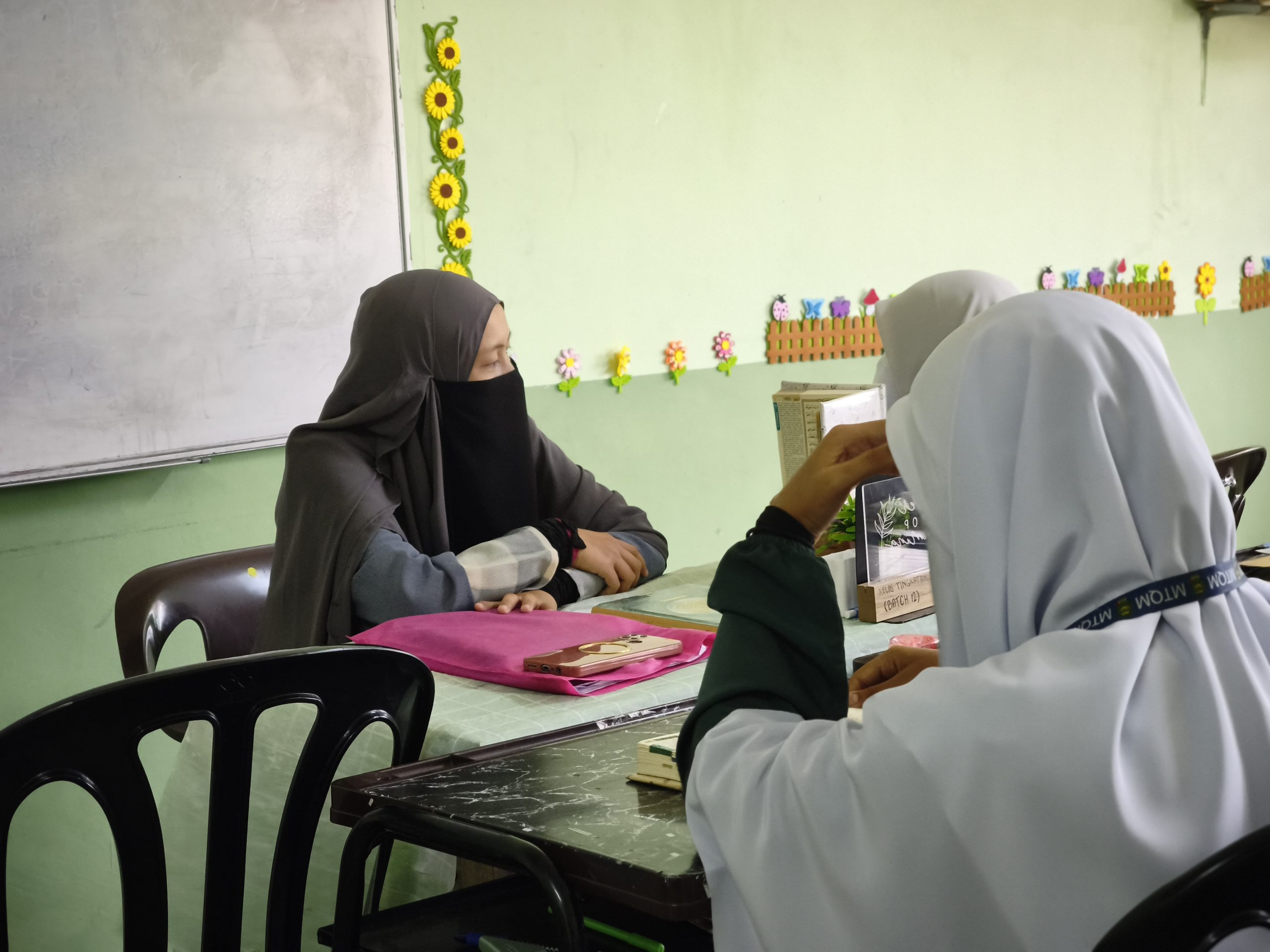 Guru tahfiz perempuan membimbing pelajar dalam sesi pembelajaran al-Quran di dalam kelas.