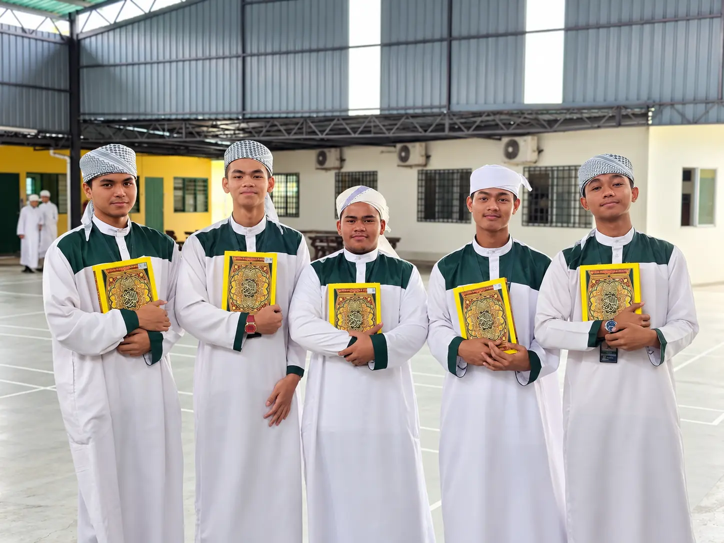 Lima pelajar tahfiz lelaki memegang Al-Quran di dewan sekolah